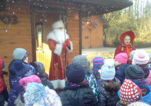 Dzieci z Mikołajem i Czerwonym Kapturkiem przed domem Świętego Mikołaja