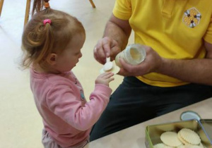 Pan Pszczelarz smaruje chleb miodem dziewczynce