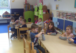 Dzieci siedzą przy stolikach, wypychają watą skarpety, z których powstaną zające