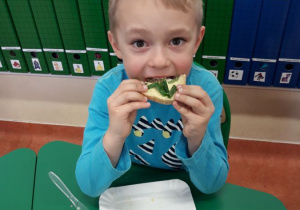 Chłopiec je kanapkę z jajkiem i szczypiorkiem