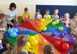 Dzieci podczas zabawy z chustą animacyjną, na której znajdują się balony