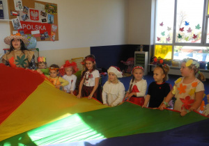 Dzieci wraz z Panią podczas zabawy na Balu jesieni z wykorzystaniem chusty animacyjnej